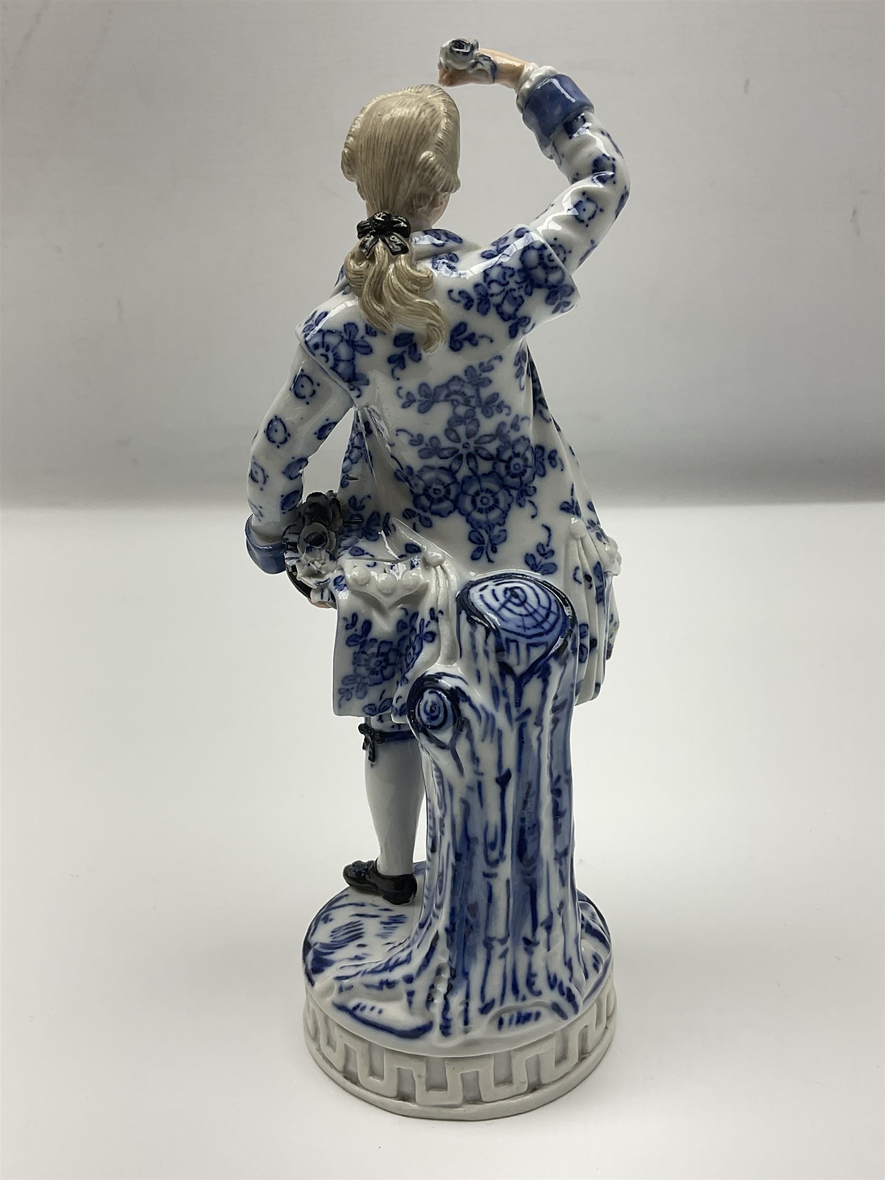 Meissen blue and white figure, modelled as a gentleman holding a hat of flowers, raised upon Greek key design base, with blue crossed swords and impressed C 73 and 149 marks beneath, H18cm