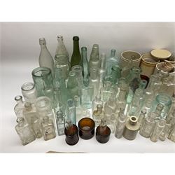 A collection of assorted glass bottles, of various size and form, mostly clear and green glass examples, plus a small group of Stoneware jars. 