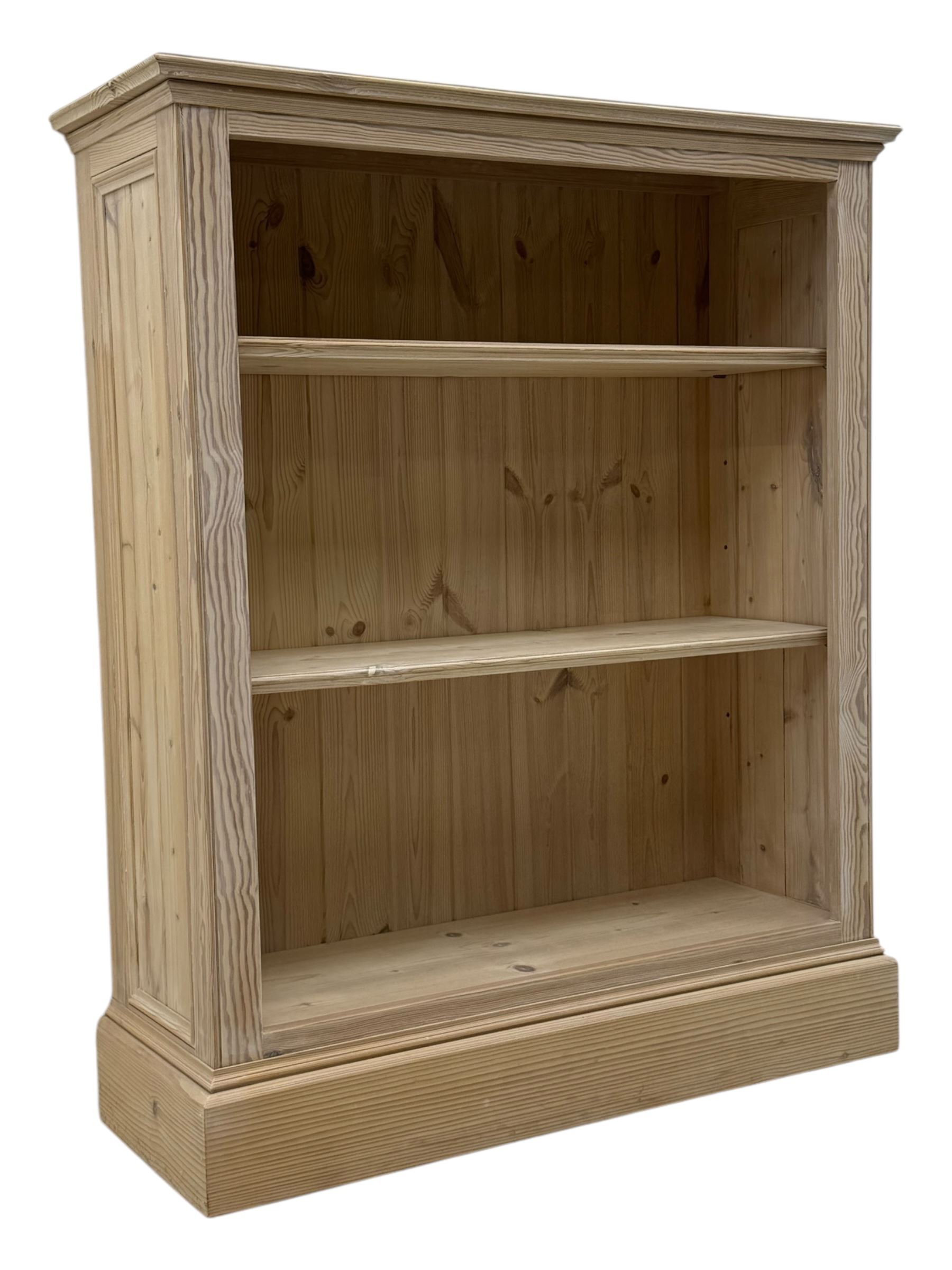 Contemporary light pine open bookcase, rectangular top with stepped moulded edge above a boarded back, fitted with two adjustable shelves, on a plinth base