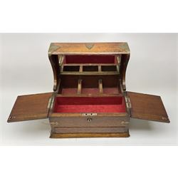 An Edwardian oak tantalus box, with brass mounts, with three recesses for decanters before a mirrored back, tand two hinged opening covers above a lower drawer, H32.5cm L36cm, D27cm. 