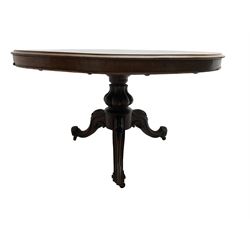 Victorian mahogany breakfast table, circular tilt-top with moulded edge, lobe carved baluster pedestal with three splayed supports, floral carvings to knees and scrolled terminals, on metal castors