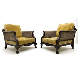Early 20th century mahogany three piece bergère suite, three seat settee and pair matching armchairs, the moulded cresting rails with carved scrolled acanthus leaves and pierced lattice decoration, acanthus carved scrolled arm terminals and shaped lower rail, on hairy paw carved feet, upholstered in gold fabric with floral pattern, loose feather cushions, double caned sides