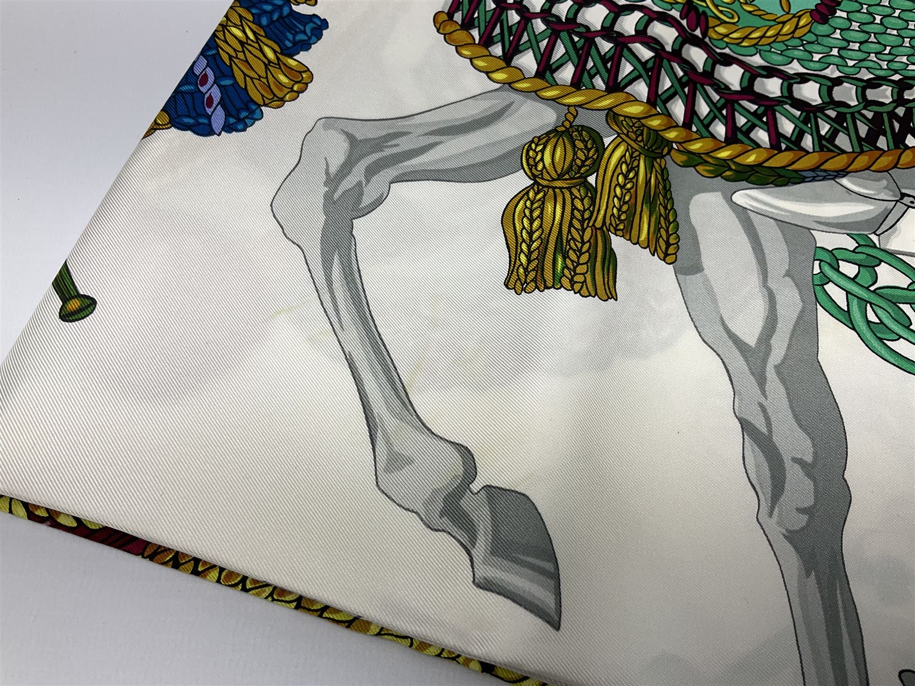 Hermès 'Le Timbalier' silk scarf, designed by Francoise Heron in 1961, printed with a central image of a gentleman on horseback donning extravagant dress, on white ground surrounded with colourful stylised knotted ropes, contained within peacock blue border, with rolled hand stitched edges and Hermes material label, 87cm square