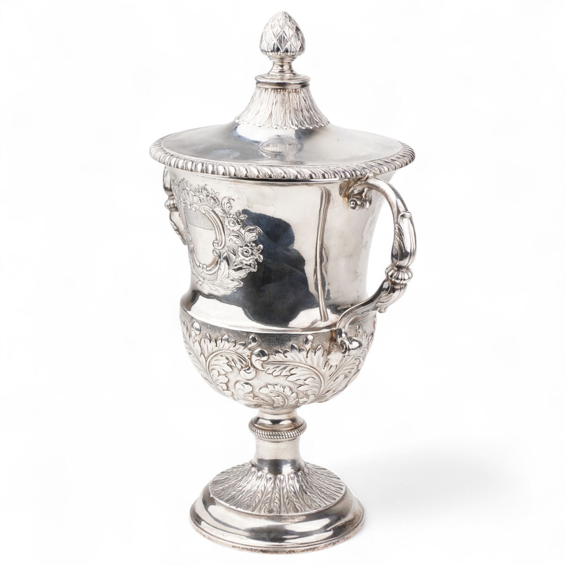 George III silver two handled campana shape cup and cover with pineapple lift, the body with cartouche surrounded by flowers above leaves and scrolls on a pedestal foot with acanthus leaf decoration H29cm London 1764, makers marks rubbed