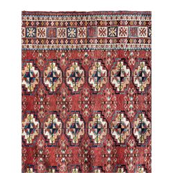 Persian Bokhara terracotta ground rug, the field decorated with six rows of repeating Gul motifs, geometric design border with rectangular repeating end panels 