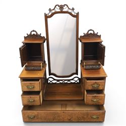 Edwardian figured walnut dressing chest, with central tilting mirror with pierced fret work, flanked by cabinet with figured walnut panelled door above a trinket drawer, with four short over a long long drawer, raised on a plinth base with castors 