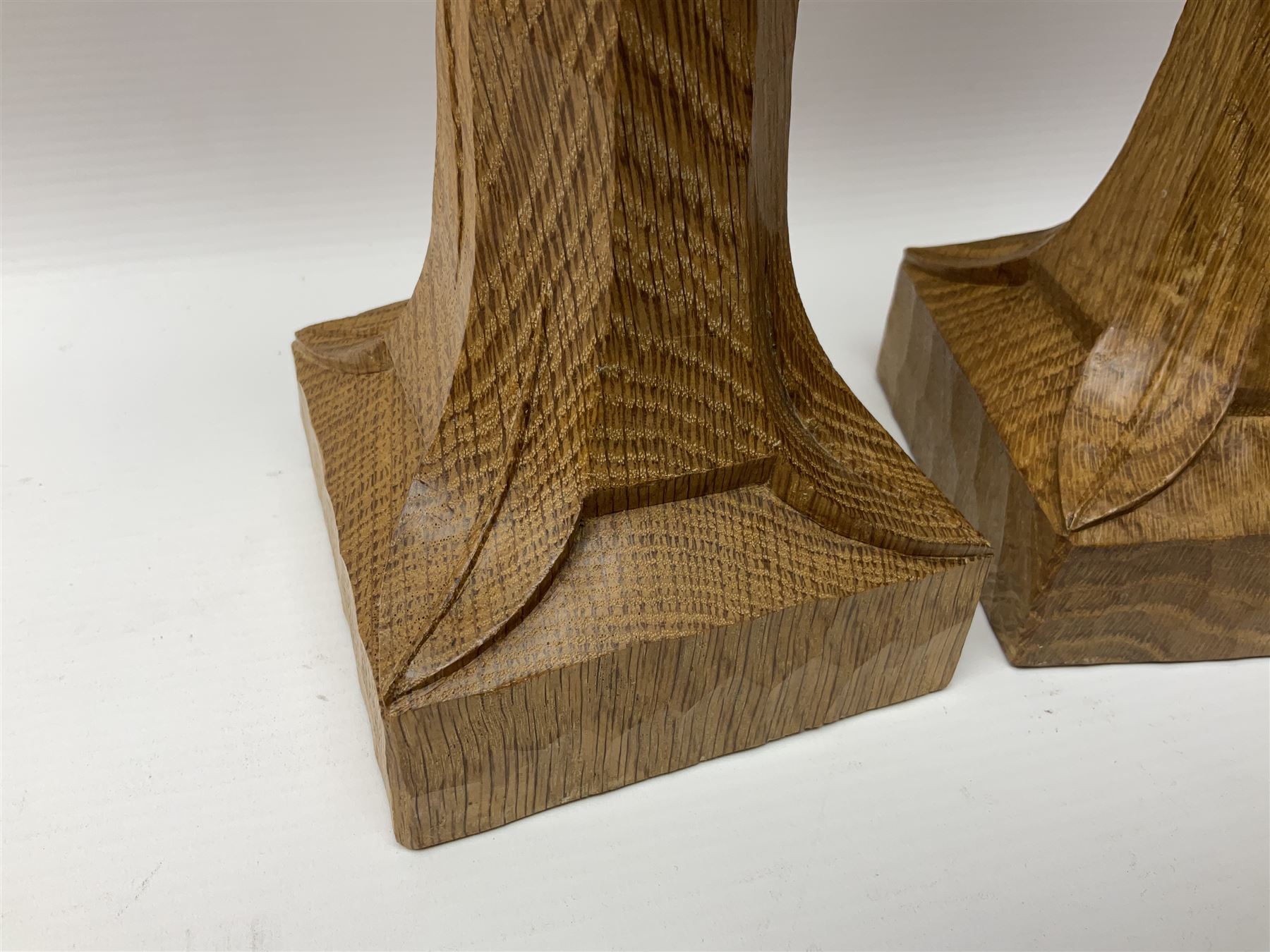 Mouseman - pair of tooled oak candlesticks, wrought iron sconce with drip tray over tapered octagonal column carved with mouse signature, terminating to stylised leaf carved square base, by the workshop of Robert Thompson, Kilburn
