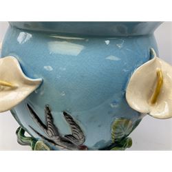 George Jones style majolica jardiniere of globular form, supported on four feet formed from modelled lily leaves growing up the side of the pot, with swallows flying amongst the white lily flowers, all set against a blue ground, with a pink interior, H27cm