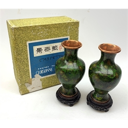 A pair of 20th century cloisonné vases, of baluster form, the dark green ground decorated with flowers, with pierced hardwood stands, vases H23cm, with box. 