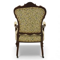 Victorian mahogany framed upholstered armchair, shaped and scroll carved cresting rail above a padded upholstered back with applied braid trim, swept open arms with carved terminals and upholstered arm pads, over a serpentine fronted deep stuffed seat, raised on cabriole forelegs terminating in carved claw feet