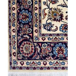 Northeastern Persian Meshed hand-knotted rug, ivory ground with an overall design of scrolling vines, palmettes, and rosettes in an indigo palette, soft blues, and madder, framed by a deep indigo border of lotus palmettes and flowerheads between multiple guard borders, 300cm x 202cm