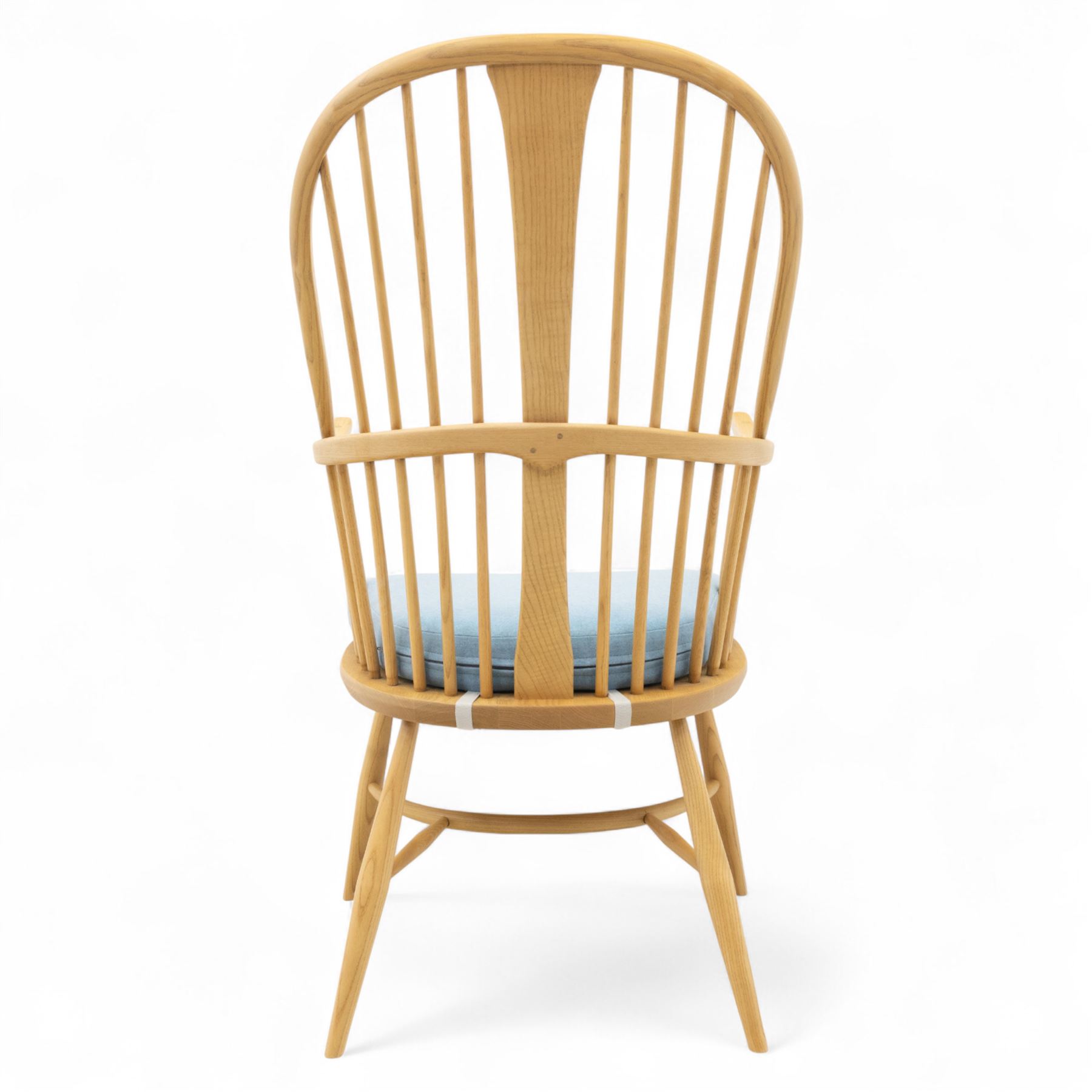 Ercol - ‘Chairmakers’ armchair, of traditional Windsor form in light ash, featuring a hoop back with four spindles and central splat, curved arms and turned supports, dished seat with upholstered blue cushion