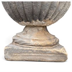 Set of three 19th century weathered carved sandstone garden urns of Neoclassical campana form, the broad everted rim carved with pointed egg-and-dart motifs, above a plain waisted bowl with gadrooned underbelly, on moulded rope-twist socle and square plinth base