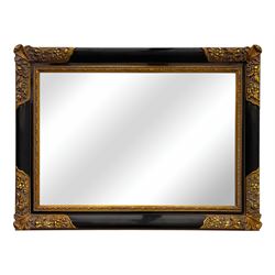 Early 20th century wall-hanging mirror, rectangular bevelled mirror plate within ebonised frame, gilt mounts to the corners carved with floral motifs 