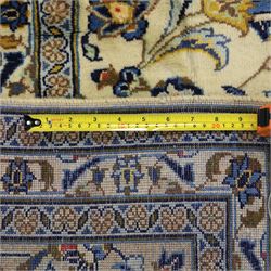 Central Persian Ardakan hand-knotted carpet, ivory field finely decorated with a symmetrical lattice of scrolling vines palmettes and flowering sprays arranged around a delicate central medallion enclosed by a pale border of stylized floral and vine ornament between multiple guard stripes with cotton fringe ends 