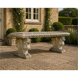 Ornate weathered cast stone rectangular garden bench, raised on winged griffin supports, square plinth bases