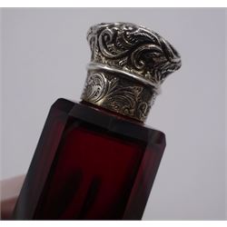 Victorian double ended ruby glass scent bottle, the faceted body with silver foliate detailed hinged cover to one end, and conforming silver screw threaded cover to the other, L13cm, unmarked but testing as silver
