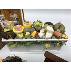 Collection of miniature dolls house grocery shop furniture and produce, comprising glazed corner counter with brass style cash register, shelved preserves unit, pies, cheese board and trays of meats, pair of white cheese counters, biscuit display with six tins, glazed preserves cabinet, pair of shop chairs and four further cheese boards complete with grapes and label flags