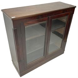 Edwardian mahogany enclosed bookcase, fitted with two glazed doors enclosing two shelves, flanked by reeded uprights, on skirted base