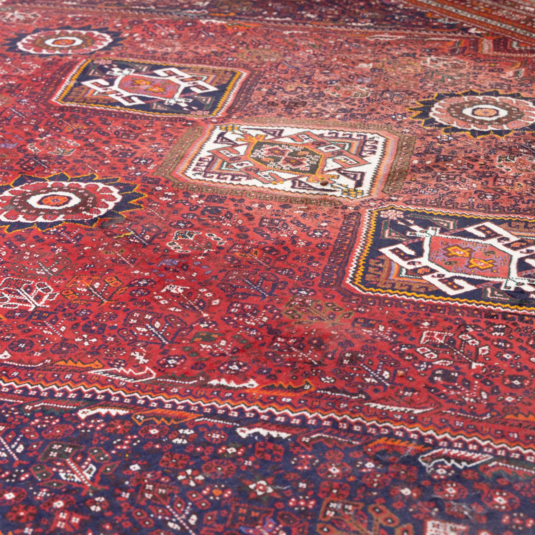 Qashqai wool carpet, red diamond-shaped field decorated with three stepped pole medallions, floral rosettes and scattered stylised motifs, within dark blue spandrels and multiple geometric guard borders