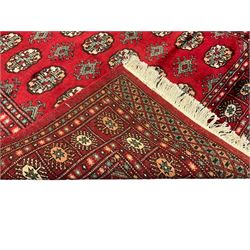 Persian Bokhara crimson ground rug, the field decorated with repeating Gul motifs and lozenges, the multi-band border with stylised plant motifs with black outlines