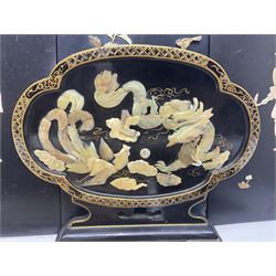 Set of four Chinese lacquered wall plaques, with applied decoration, depicting birds amongst peonies, together with a similar table screen, with mother of pearl dragon decoration and a small Oriental rug, decorated with a bird and peonies, with fringe edging, rug without fringe H33cm