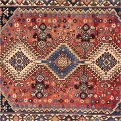 Persian Shiraz rug, wool on cotton foundation, with central row of linked diamond medallions in ivory, indigo and madder tones, stylised rosettes and angular vine motifs throughout, framed by a geometric border