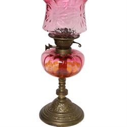 Victorian oil lamp, the brass base supporting cranberry glass reservoir, with clear glass chimney and cranberry shade with fluted rim, overall H59cm