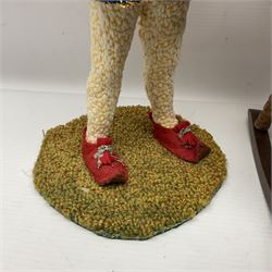 Anna Meszaros Hungary - three hand made needlework figurines - 'The Cobbler' as a child seated in a wooden rocking chair working on a removed boot H28cm; young girl in a long floral dress standing playing a harp H35cm; and young girl wearing a blue tabard standing playing a lute (3) Auctioneer's Note: Anna Meszaros came to England from her native Hungary in 1959 to marry an English businessman she met while demonstrating her art at the 1958 Brussels Exhibition. Shortly before she left for England she was awarded the title of Folk Artist Master by the Hungarian Government. Anna was a gifted painter of mainly portraits and sculptress before starting to make her figurines which are completely hand made and unique, each with a character and expression of its own. The hands, feet and face are sculptured by layering the material and pulling the features into place with needle and thread. She died in Hull in 1998.  