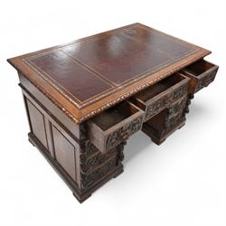 Victorian carved oak twin pedestal desk, moulded and foliate carved rectangular top with leather inset, fitted with nine drawers, each carved with scrolling foliage and lion mask handles, on skirted base 