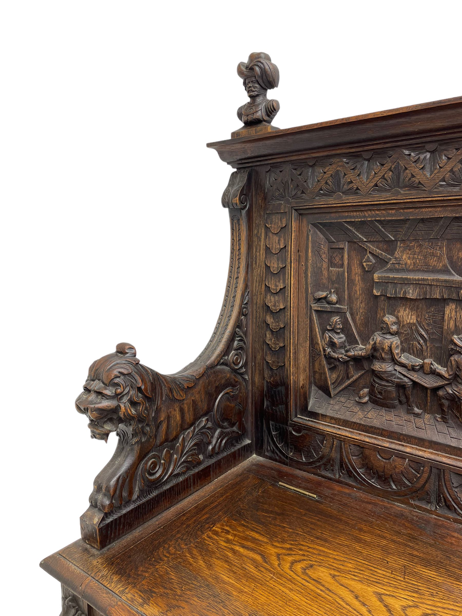 19th century heavily carved oak settle, the moulded upper rail over triangular foliage carved frieze, three Flemish style carved panels depicting tavern scenes, acanthus carved uprights terminating to lion carved arms, hinged box seat, the panelled front carved with lion masks and extending scrolled acanthus leaves, on moulded skirt base