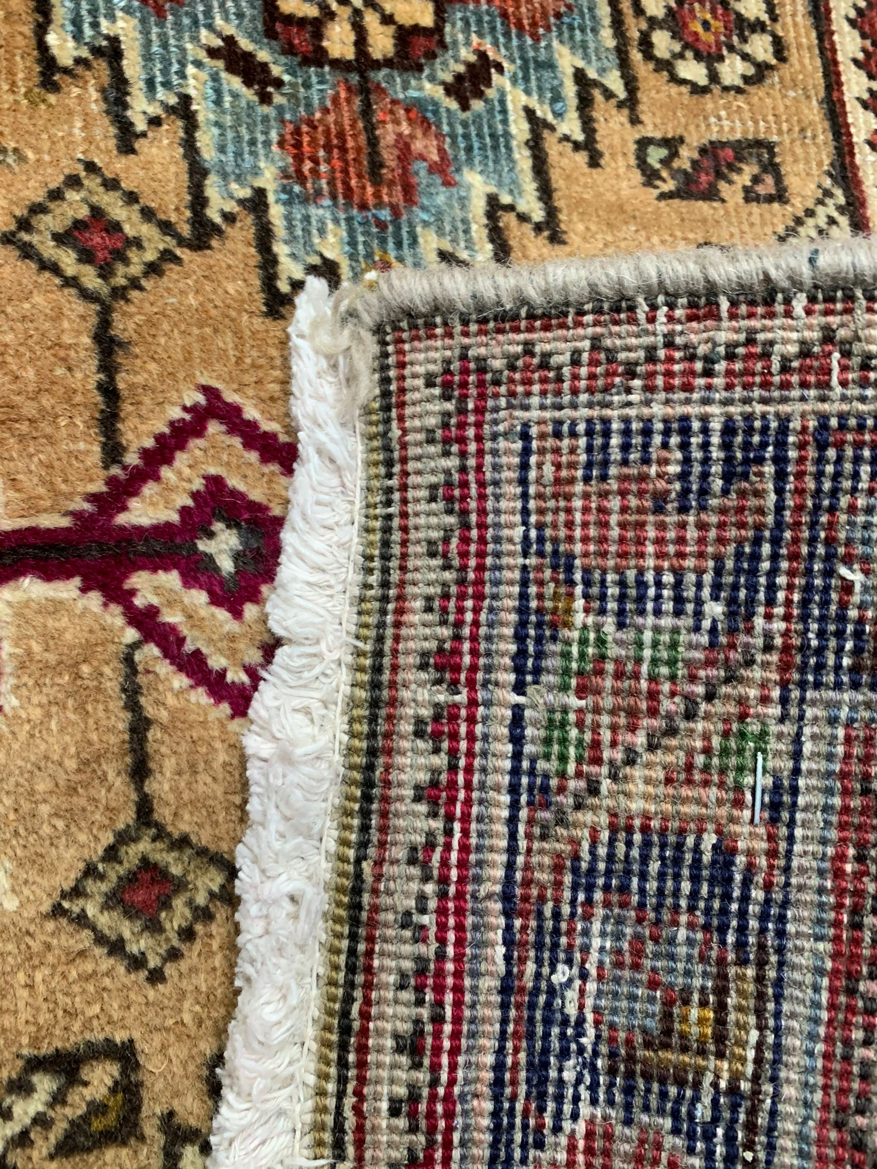 Persian Azarbaijan golden ground carpet, the shaped crimson ground medallion decorated with geometric motifs, the field profusely decorated with stylised plant and flower head motifs, repeating border with guard bands 