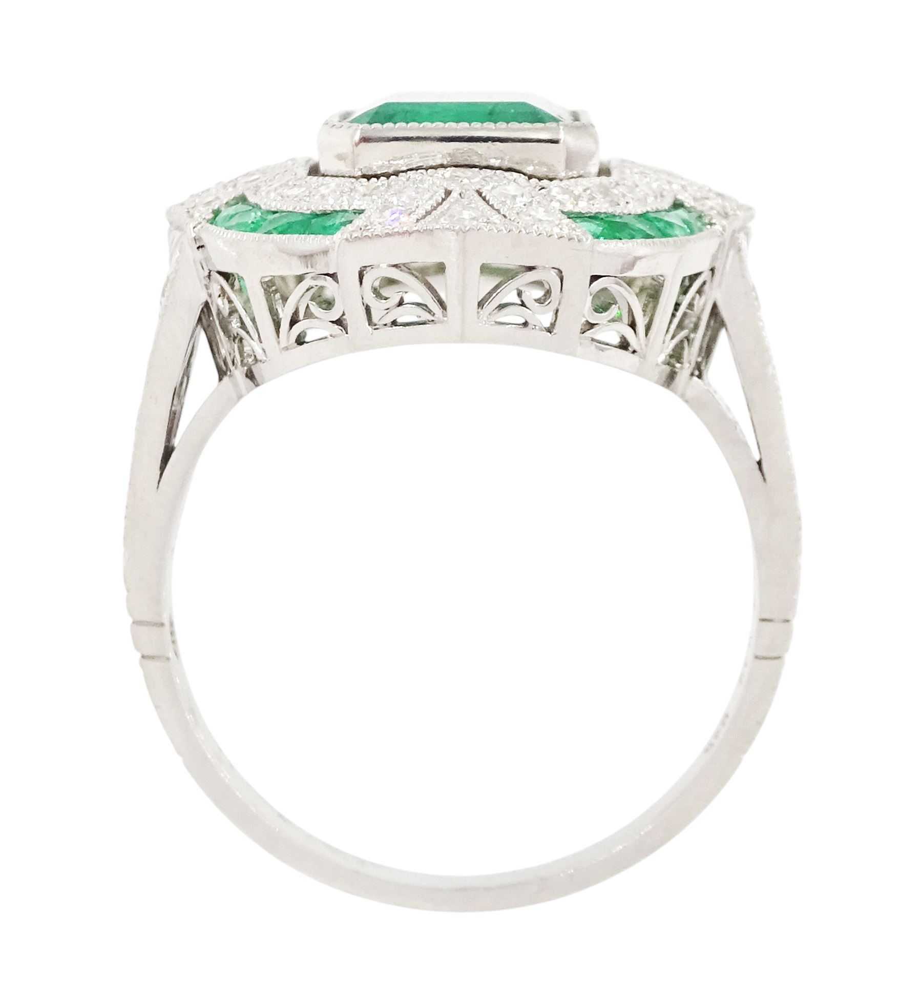 Platinum emerald and diamond milgrain set dress ring, single octagonal cut emerald of 2.40 carat, surrounded by single cut diamonds and a border of calibre cut emeralds, with fancy pierced design gallery diamond and engraved flower head shoulders, stamped 850 Plat