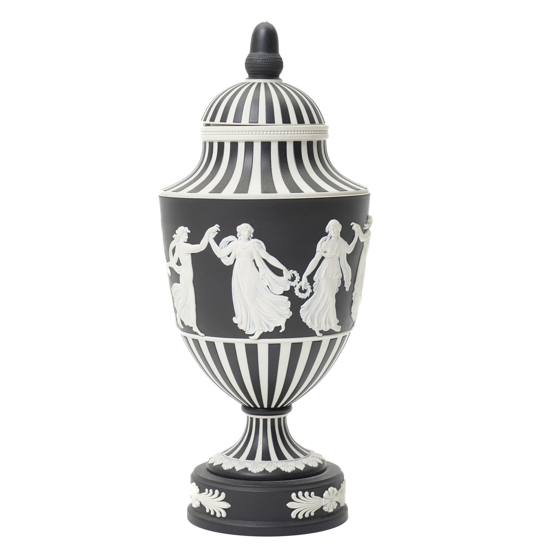 Wedgwood 20th century 'Dancing Hours' jasperware urn, the upper section decorated with a single band of neoclassical maidens in white to a black basalt ground, rising from a circular plinth decorated with foliate motifs, complete with cover with acorn finial, stamped 'Wedgwood Made in England', H25cm 