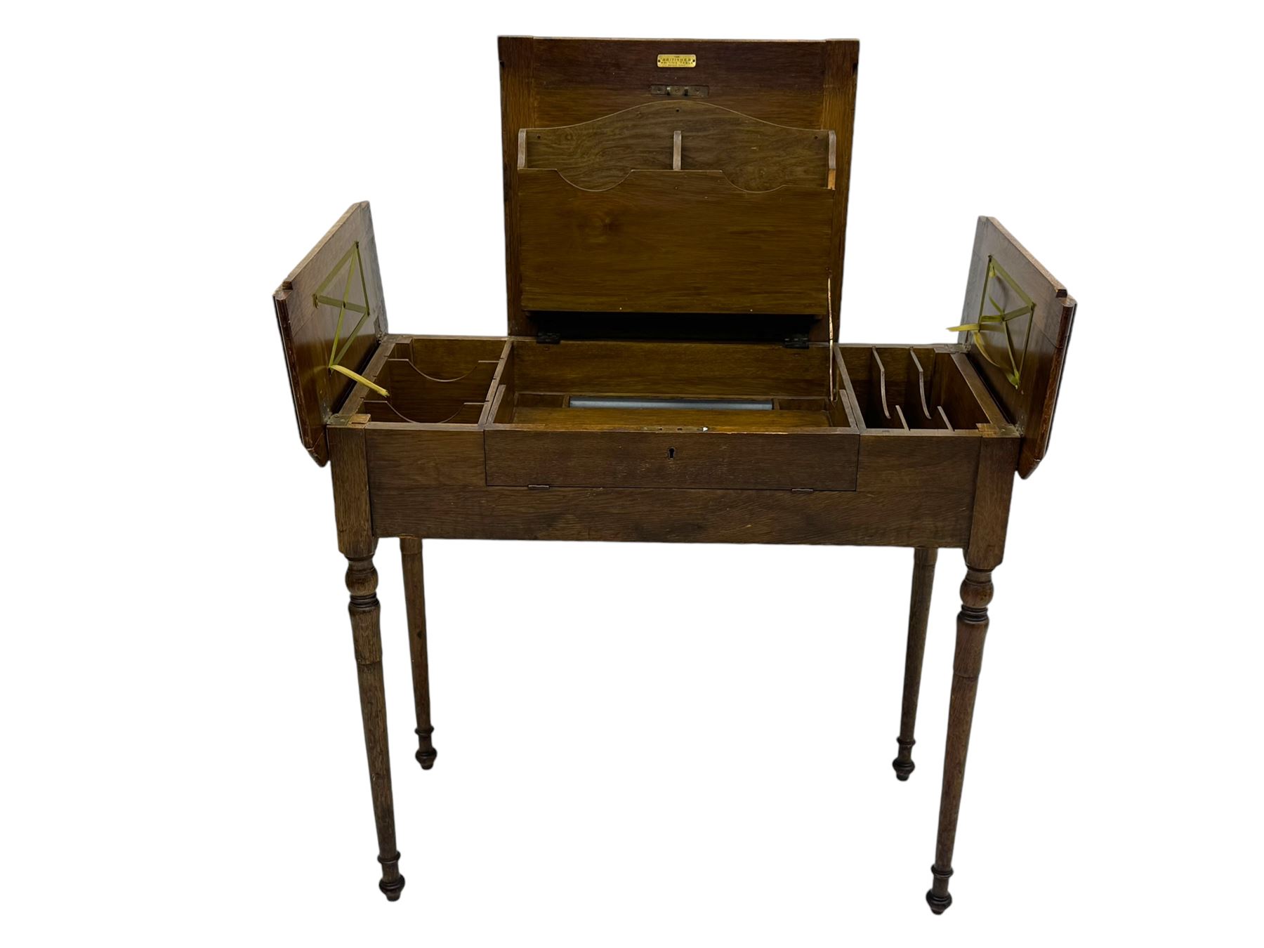 Edwardian oak metamorphic 'Britisher Writing Table', rectangular hinged top revealing correspondence compartments and hinged writing surface with underside storage, flanked by twin hinged compartments with dividers, on turned supports