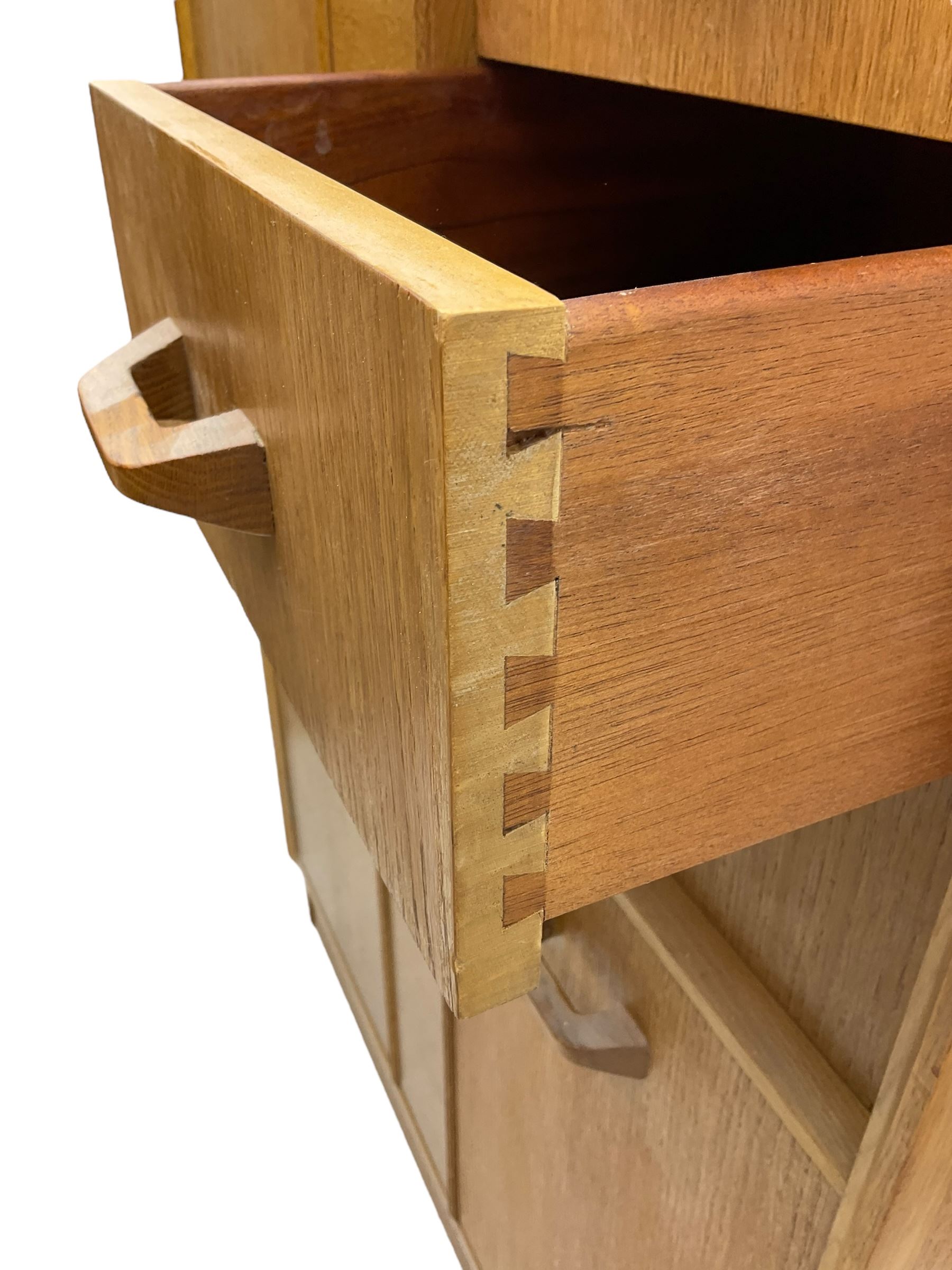 G-Plan - mid 20th century teak tallboy or combination wardrobe, left side with full-height hanging cupboard, right side with three drawers, the top fitted with vanity mirror, above cupboard with shelves, raised on a plinth base