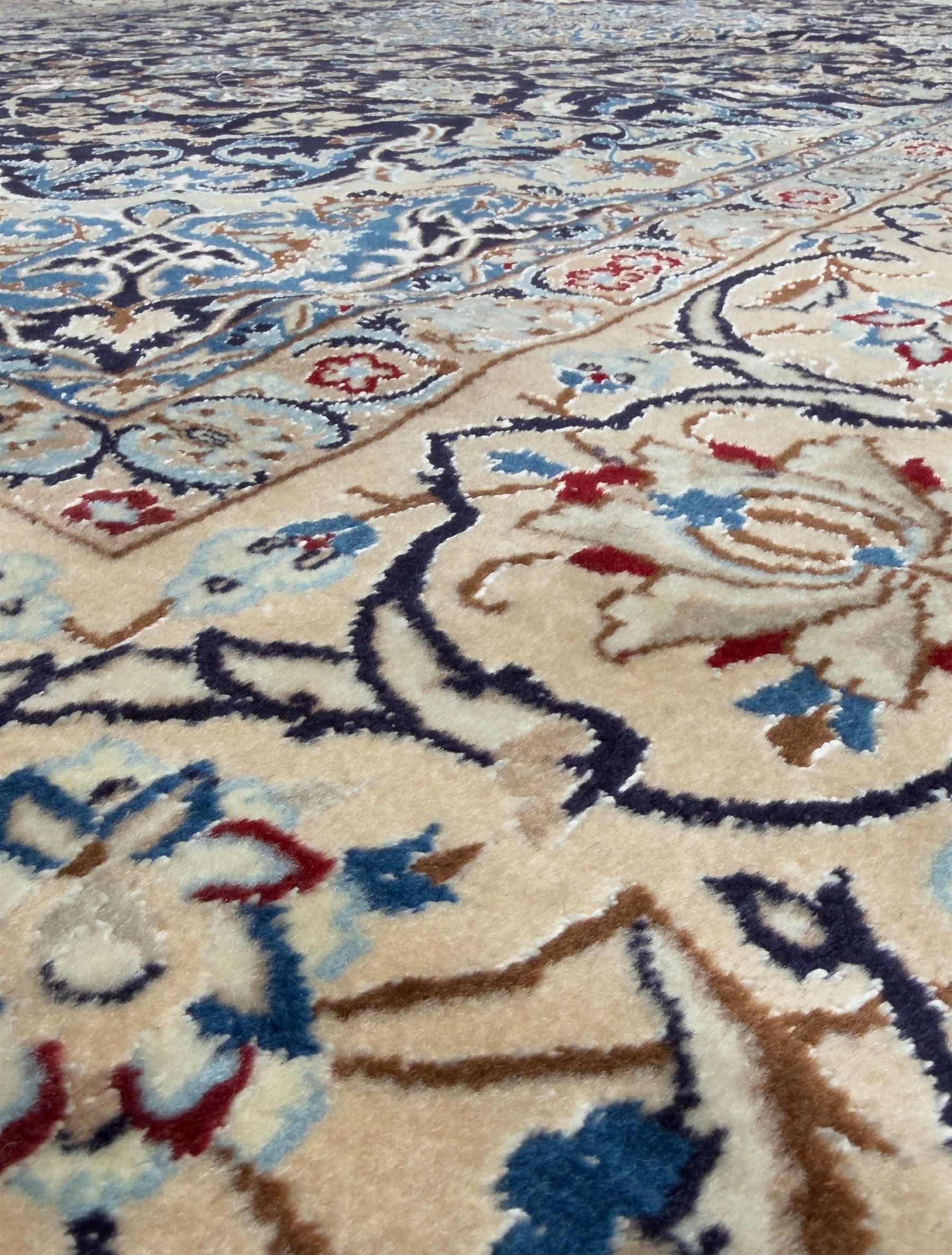 Central Persian Nain carpet, the deep blue field with finely drawn scrolling palmettes and flowering vines around a central ivory and sky blue rosette medallion, enclosed by an ivory border of interlaced floral arabesques and lotus forms between multiple guard stripes, from the region of Nain