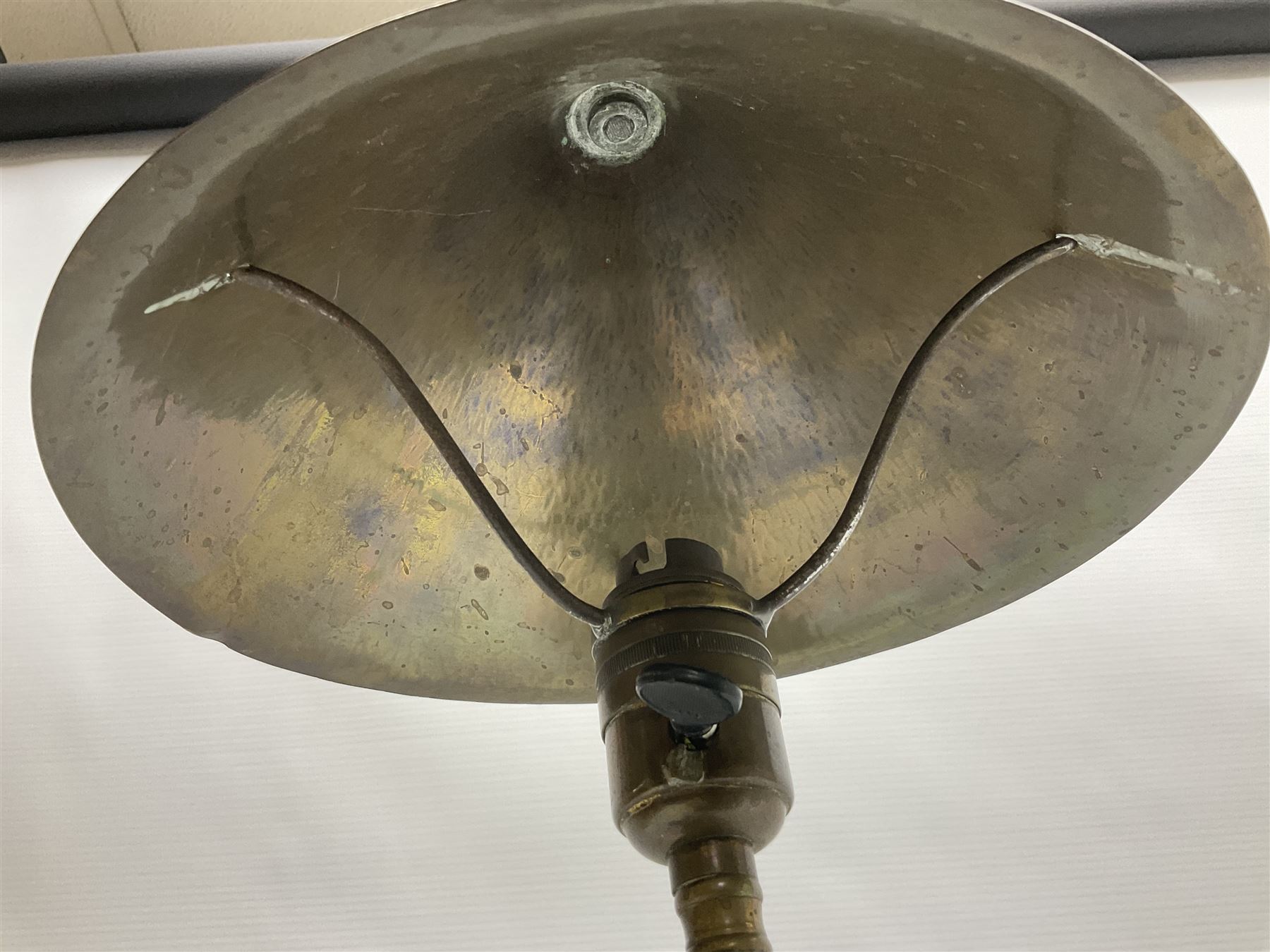 Arts & Crafts Jesson, Birkett & Co, brass table lamp or wall light, designed by Thomas Birkett, the tapering stem with adjustable ball pivot supporting a conical shade with tapering final with ball terminal, upon a circular domed base pierced for wall mounting, shade positioned upright overall H57cm

Often misattributed to Arthur Stansfield Dixon for Birmingham Guild of Handicraft, this particular lamp was designed by Thomas Birkett.
In the late 1890's Birkett worked as a metalwork at the Birmingham Guild, before later joining the Faulkner Bronze Company which went on to become Jesson, Birkett & Co in 1904. The lamp features in lighting catalogues from the firm under the model no E490.

