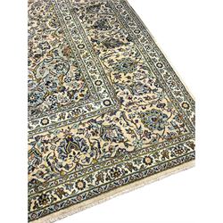 Central Persian Kashan pale khaki ground carpet, shaped central medallion enclosing small stylised motifs, the field decorated profusely with trailing foliate branches and plant motifs, guarded border with repeating floral design 