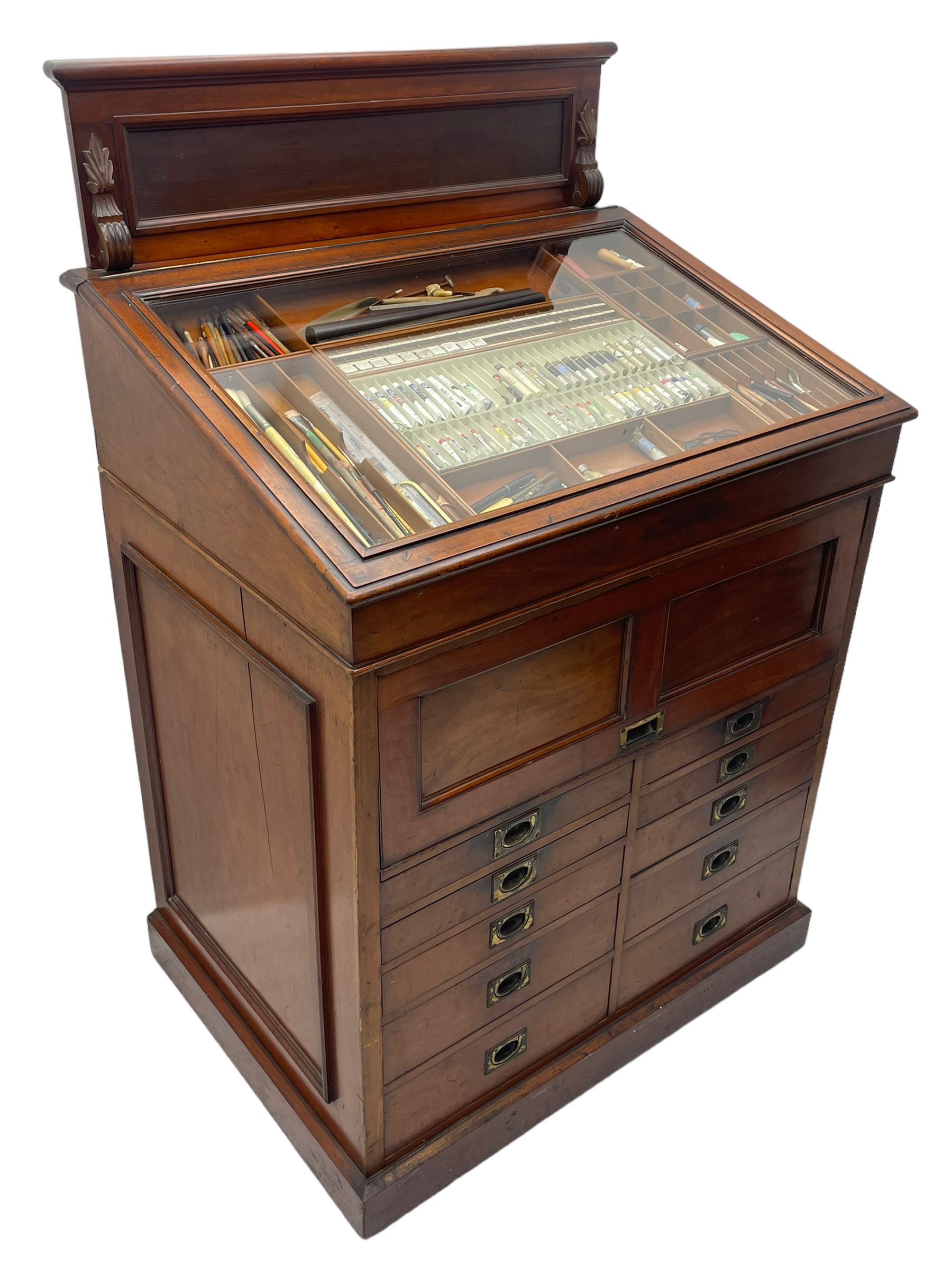 Edwardian mahogany artist's cabinet once belonging to the British artist Eli Marsden Wilson (1877-1965), raised panelled back mounted by carved brackets, sloped and hinged glazed lid enclosing paint holders and compartments, up-and-over panelled door revealing three slides, fitted with two banks of five graduating drawers with recessed brass handles, on skirted base.

Together with a quantity of artists' equipment and tools including paints, paintbrushes, charcoal, chalks, etc. and various prints relating to the life of the artist, including Quaker anti-war posters, Victorian Stevengraphs, and various chromolithographs 

Provenance: Removed from the studio of Eli Marsden Wilson. The cabinet comes to us for sale through family descent. The vendor is descendant of Marsden. Many further etchings removed from the cabinet are being sold in the Spring Art Sale, Friday 15th March 2024, Lots 265-271.

Notes: born in Ossett, Eli Marsden Wilson was the only son of Alfred Wilson, a foreman beamer, and Emma Marsden, and had five sisters. After studying at Wakefield College of Art, he moved to the Royal College of Art in London, where he became a pupil of Sir Frank Short. He had his first exhibit at the Royal Academy in 1905, the same year he married fellow artist Hilda Mary Pemberton.

A Quaker, vegetarian, and pacifist, he was a conscientious objector in World War I and as such was imprisoned in 1917 for two years. In September 1922 he was commissioned by Princess Marie Louise to produce miniature etchings for Queen Mary's Dolls' House at Windsor Castle; two such etchings are being sold in the Spring Art Sale, Friday 15th March 2024, Lot 265.