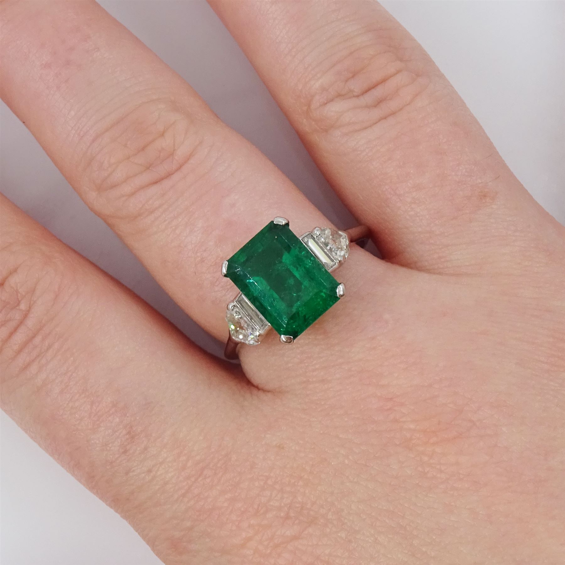 Platinum Colombian emerald and diamond ring, single emerald cut emerald of approx 3.00 carat, each side set with a single baguette cut and heptagonal cut diamond, with The Gem & Pearl Laboratory report