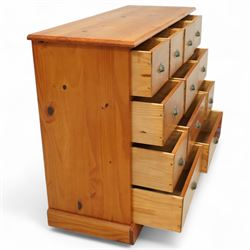 Late 20th century pine merchants chest, rectangular top over an arrangement of twelve small and four larger drawers, each with recessed panel facias and brass cup handles, plinth base