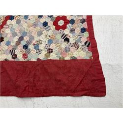 19th century patchwork quilt, hand stitched from hexagons of various materials including printed patterned and floral examples, featuring repeating large central hexagon to centre, the top and bottom with thick panel red jacquard border, the sides bordered with plain red fabric, lined with panels to reverse, 180 x 190 cm