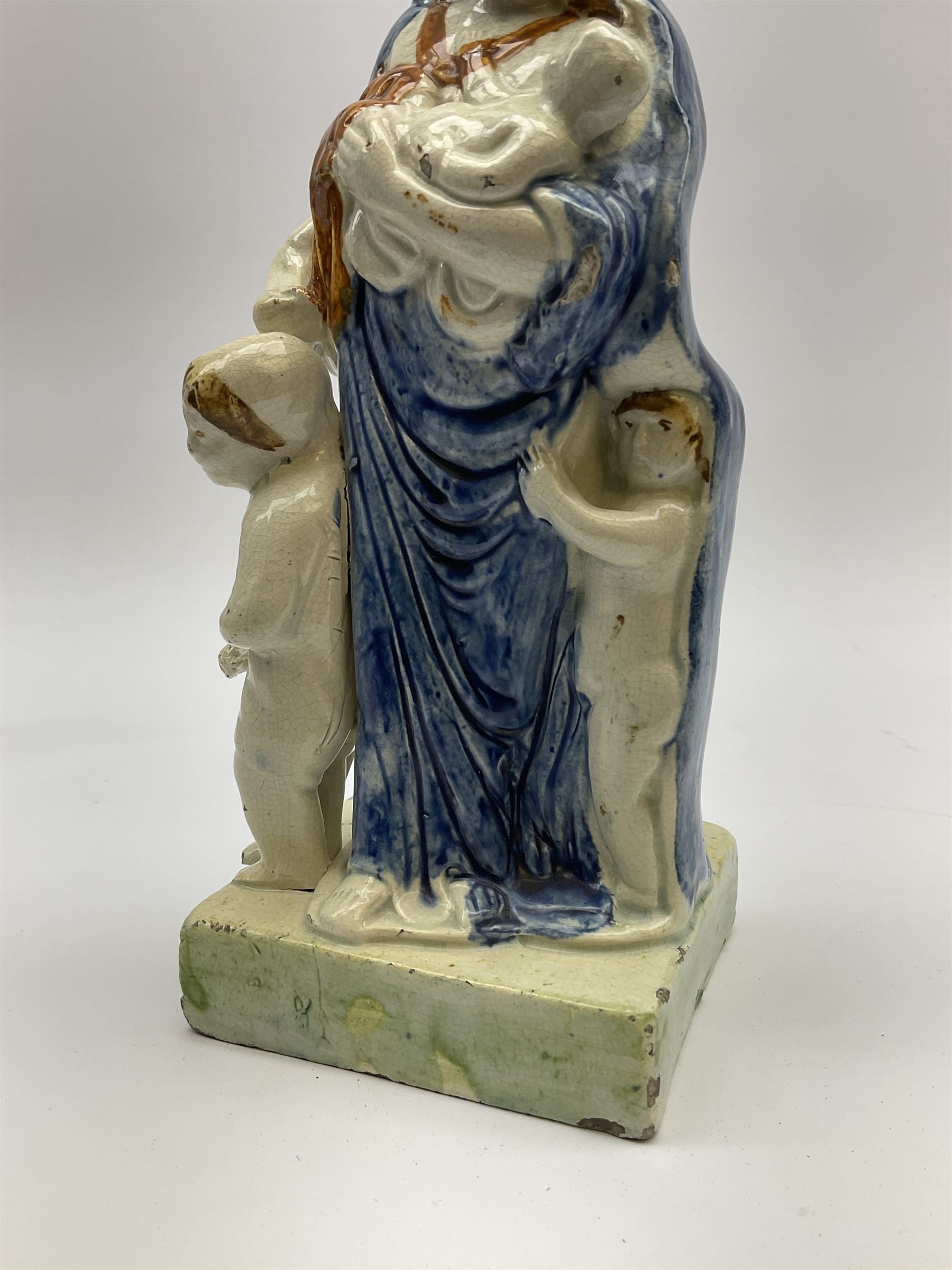 Late 18th century Prattware figure representing Charity, modelled as a mother with baby in her arms and two small children clutching at her robes, upon a square base, overall H21cm.