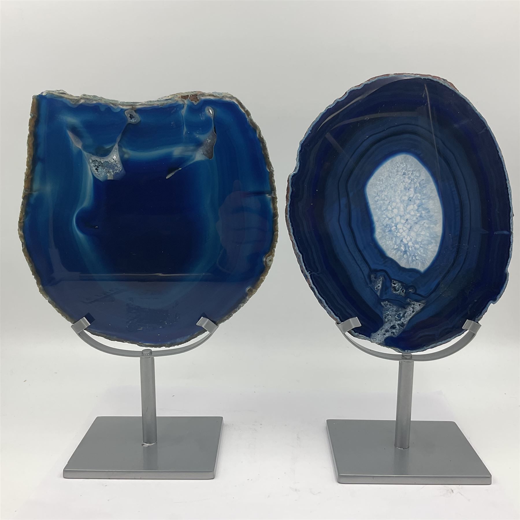 Pair of blue agate slices, polished with rough edges, raised upon silvered metal stands, H26cm