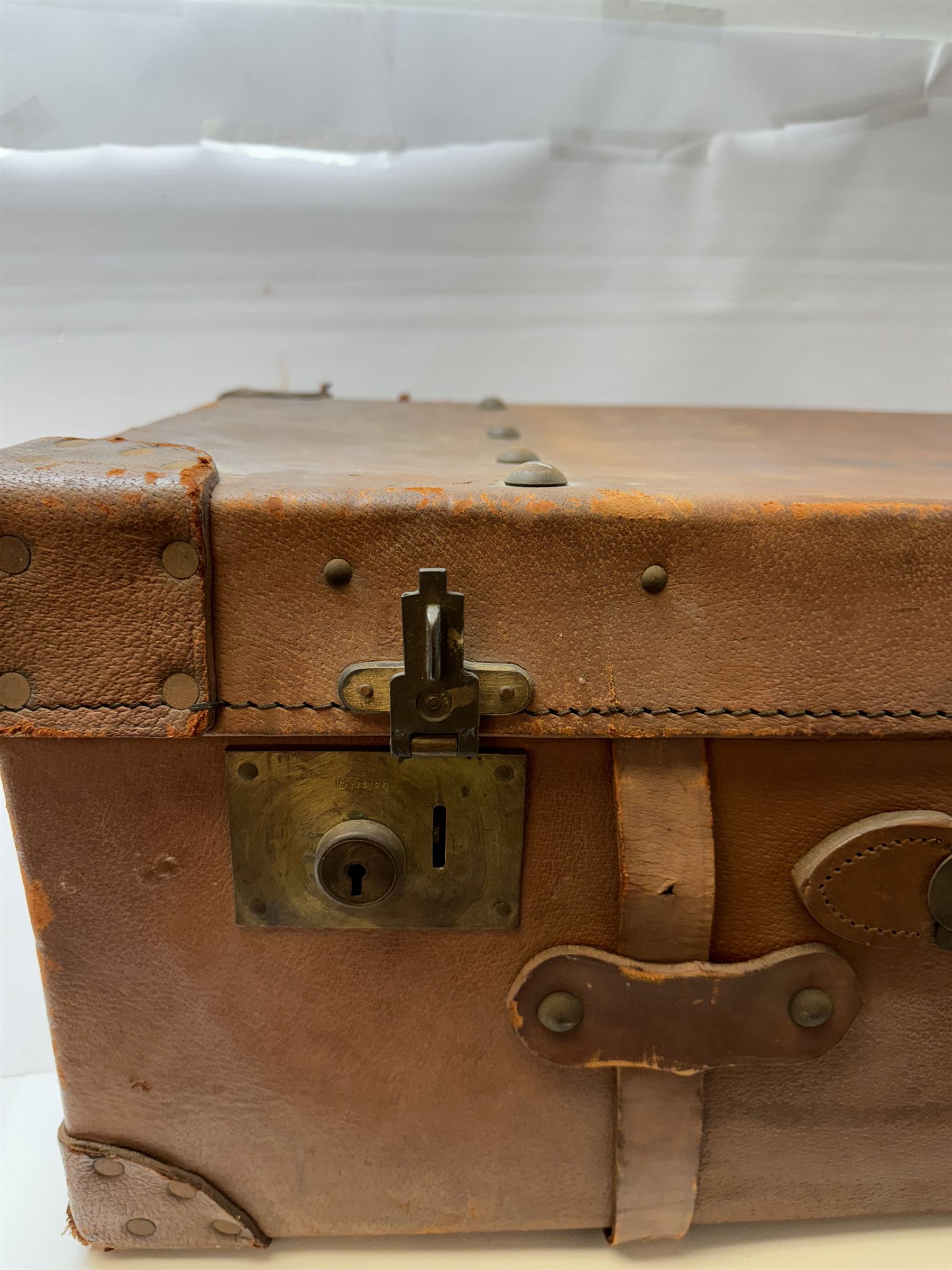 Early 20th century leather trunk, with brass fixtures, leather straps and buckle fastenings, embossed to the top with initials GG, H28cm, W76cm