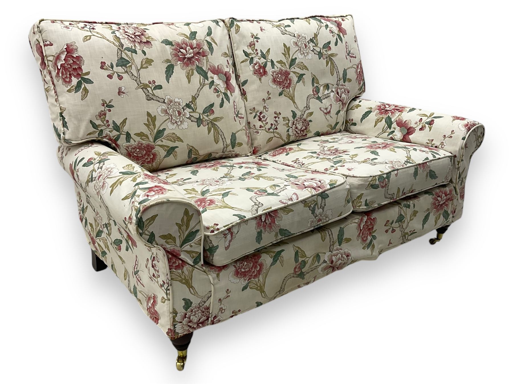 Steed Upholstery - 'Knightsbridge' two seater sofa, upholstered in cream fabric with pink and green floral design, loose back and seat cushions, raised on mahogany supports with brass castors