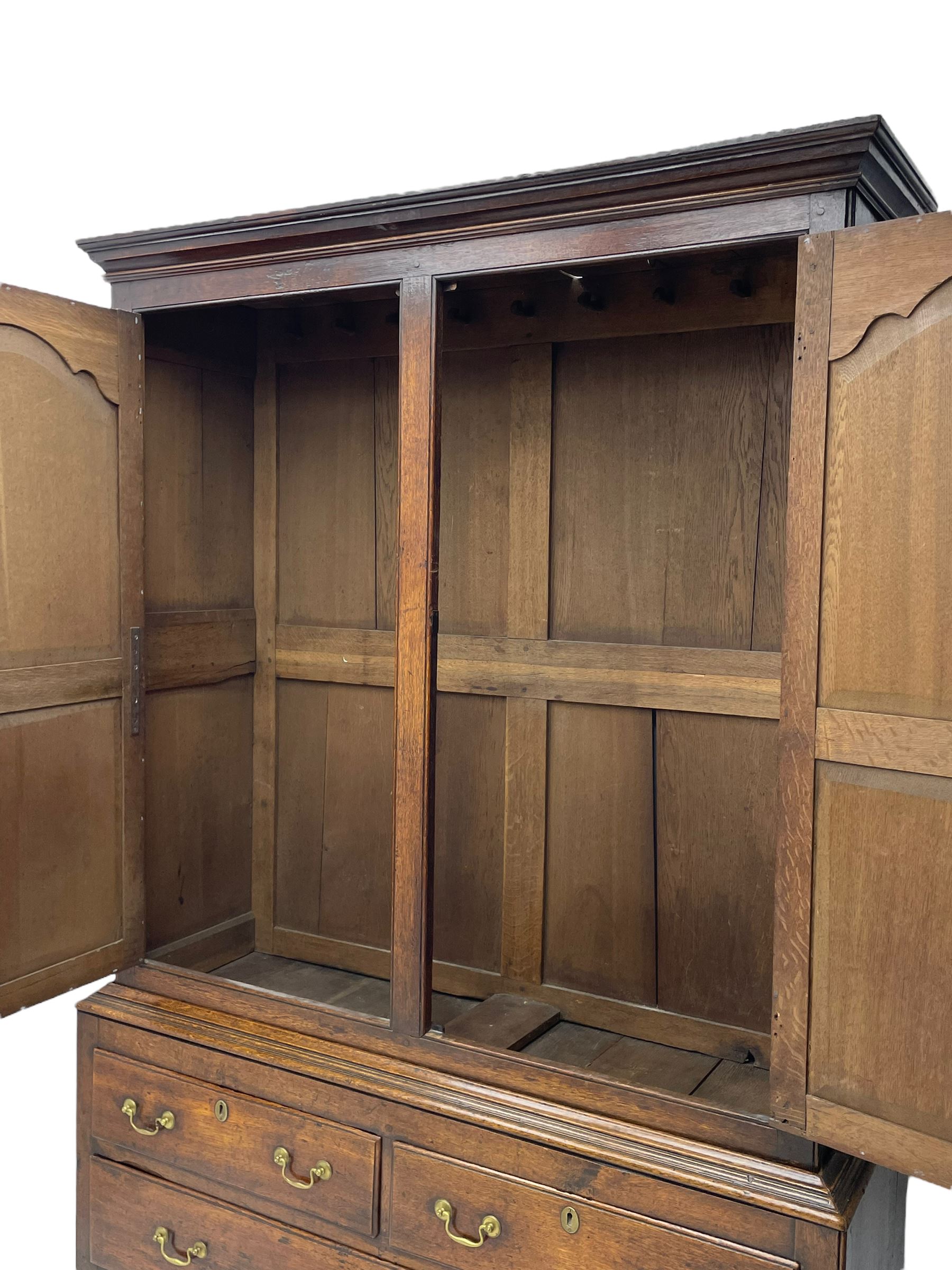 George III oak livery cupboard, projecting moulded cornice over two panelled doors, the upper panels within stepped ogee and arched moulded frame, the interior fitted with a single row of wooden hooks, two short and one long drawers, on bracket and return skirted base 