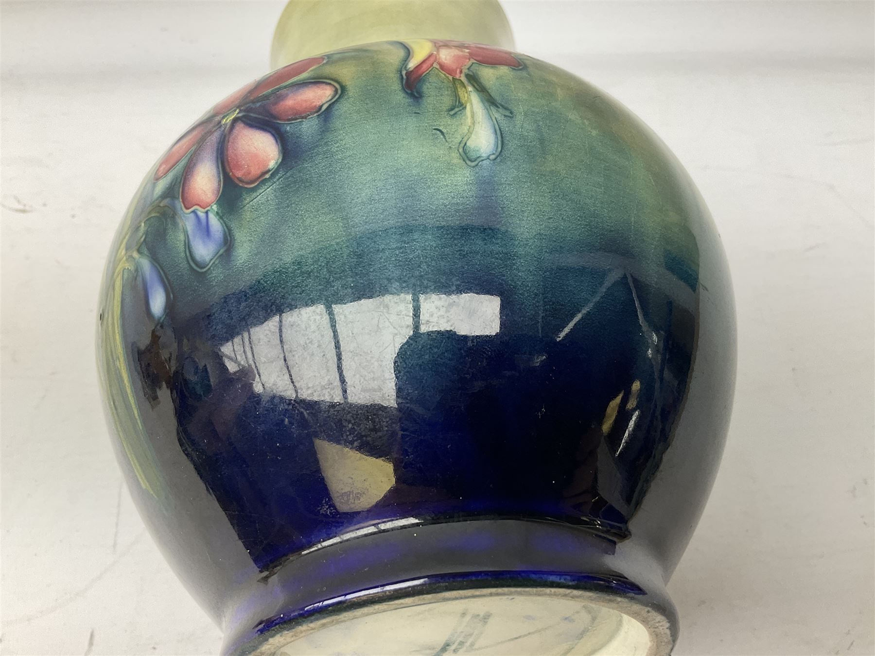 Moorcroft vase of baluster form decorated in the Spring Flowers pattern upon a merging green and blue ground, with impressed and painted marks beneath, H22.5cm