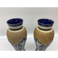 Pair of Royal Doulton Lambeth stoneware baluster vases, decorated in light relief with panels of foliage on blue ground, with gilt scrolls above, impressed mark beneath, 28cm high